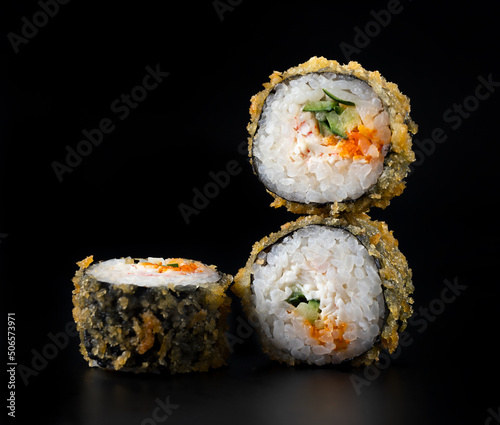 fried rolls with crab and cucumber on black background