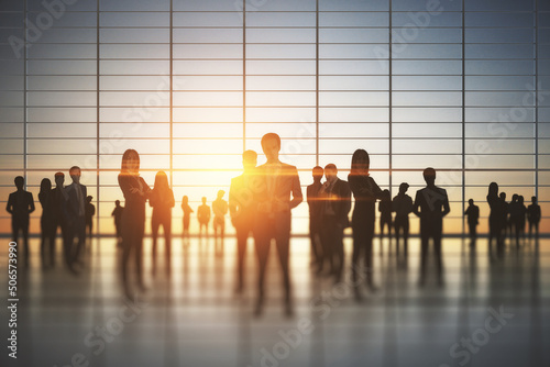 Business teamwork and corporate work concept with people silhouettes in spacious office hall at sunset