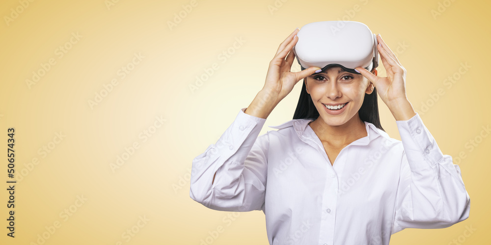 Virtual reality concept: smiled young girl in light shirt with white VR glasses on her head on light orange background with place for your logo or text, mockup Virtual reality concept: smiled young girl in light shirt with white VR glasses on her head on light orange background with place for your logo or text, mockup