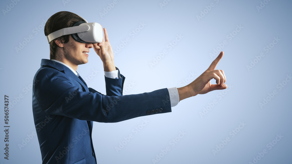 Young businessman working in virtual reality office in VR glasses, presses his finger virtual interface on abstract light blue backdrop. Innovate and future technology concept, close up Young businessman working in virtual reality office in VR glasses, presses his finger virtual interface on abstract light blue backdrop. Innovate and future technology concept, close up