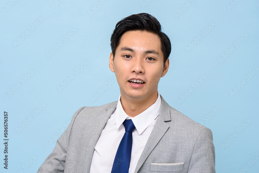 Portrait of young handsome Asian man in formal business suit on isolated light blue studio background Portrait of young handsome Asian man in formal business suit on isolated light blue studio background