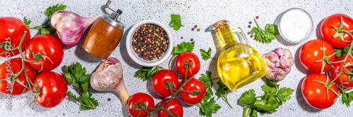 Cooking ingredients background. Spices, black pepper, garlic, onion, greens, tomatoes. olive oil on white stone concrete table top view copy space. Preparation healthy food background.