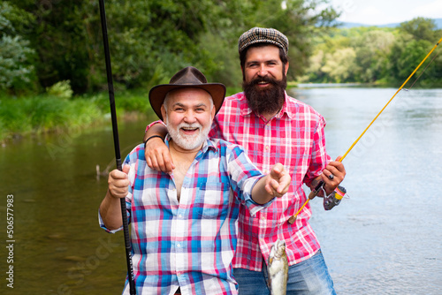 Man friends. Father and mature son fisherman fishing with a fishing rod on river.
