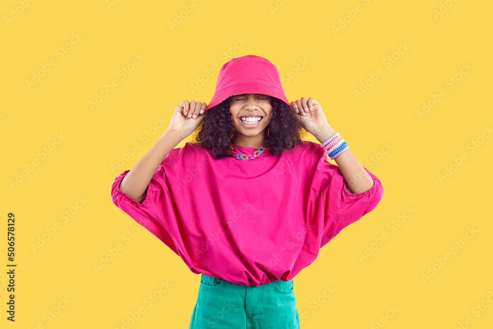 Happy joyful kid in trendy casual outfit puts pink bucket hat on