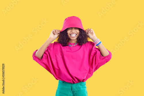 Fotografiet Happy joyful kid in trendy casual outfit puts pink bucket hat on her head