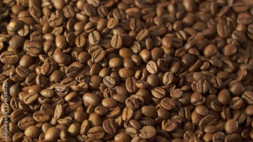 Coffee beans in rotation. Mixed Robusta and Arabica roasted Coffee beans. Coffee background. Close up of seeds of coffee. Coffee beans in rotation. Mixed Robusta and Arabica roasted Coffee beans. Coffee background. Close up of seeds of coffee.
