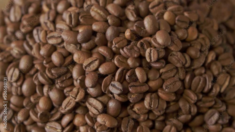 Coffee beans in rotation. Mixed Robusta and Arabica roasted Coffee beans. Coffee background. Close up of seeds of coffee.