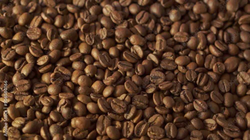 Coffee beans in rotation. Mixed Robusta and Arabica roasted Coffee beans. Coffee background. Close up of seeds of coffee. Coffee beans in rotation. Mixed Robusta and Arabica roasted Coffee beans. Coffee background. Close up of seeds of coffee.