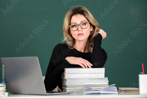 Pretty young high school or college teacher on the chalkboard. Closeup portrait of young sexy caucasian female teacher portrait with blackboard background.