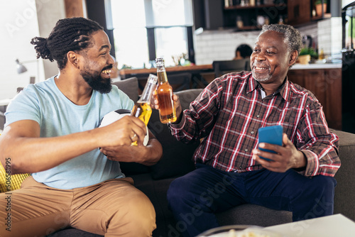 Obraz na plátně Man with senior father watch football together with beer celebrating