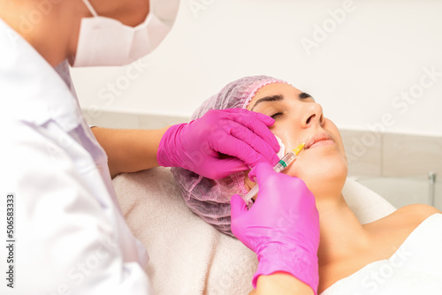 Young caucasian woman getting botox injection with hyaluronic acid in the lips at a beauty clinic