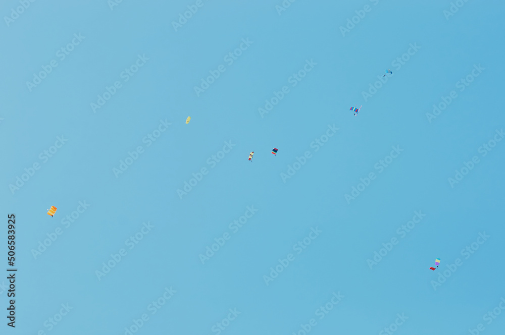 A group of parachutists in a clear sky with colored bright parachutes. A group of parachutists in a clear sky with colored bright parachutes.