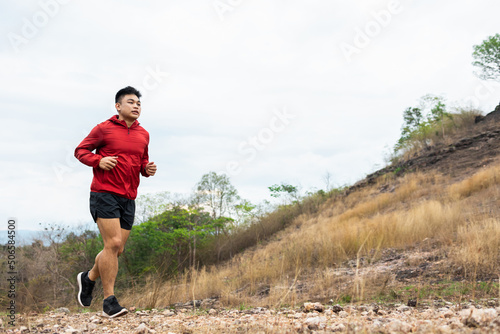 Trail runner man running on rocky mountain. Athlete jog exercising outdoor for healthy. Confident and powerful marathon man running workout and cardio. Sport and Lifestyle concept. © Chanakon