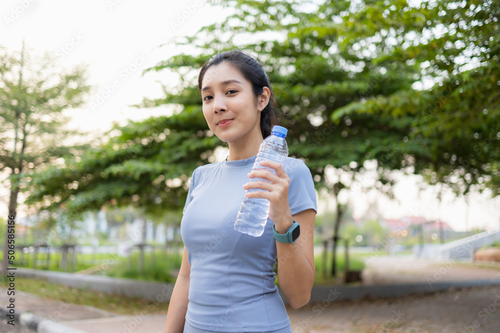 Happy slim woman drinking water after workout exercising in the city at sunrise. Young beautiful asian drinking water after jogging running outdoor. Healthy and active lifestyle concept. Happy slim woman drinking water after workout exercising in the city at sunrise. Young beautiful asian drinking water after jogging running outdoor. Healthy and active lifestyle concept.