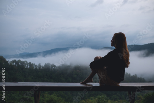 Fotografie Portrait image of a woman sitting on wooden balcony with a beautiful mountains a