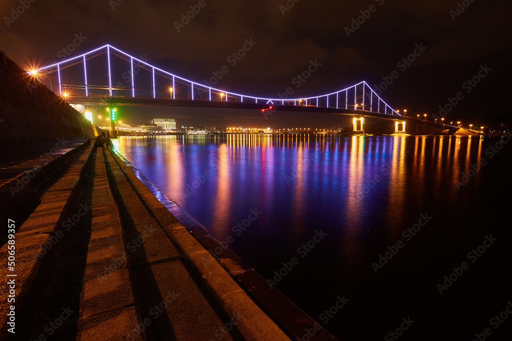 Night city landscape. Pedestrian bridge across the Dnieper river, Kyiv, Ukraine