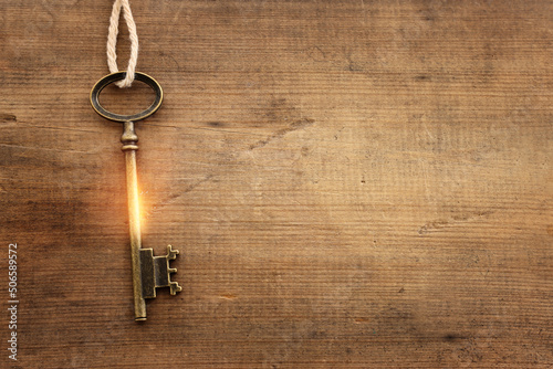 Fotografie Top view image of old key with golden light over wooden background
