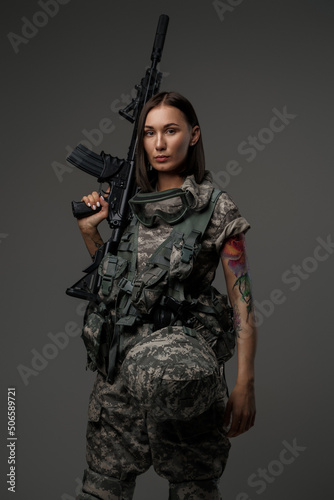 Shot of militant woman dressed in camouflage protective uniform looking at camera. © Fxquadro