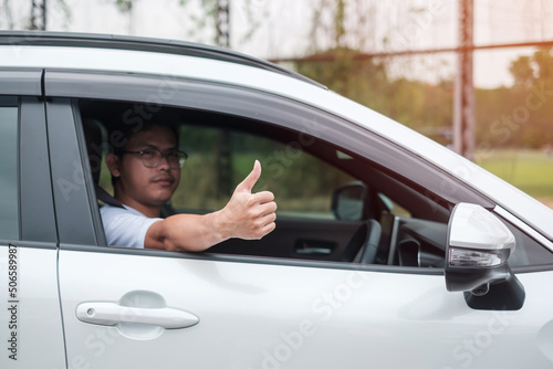 man hand Thumb up during driving a car on the road, hand controlling steering wheel in electric modern automobile. Journey, trip and safety Transportation concepts