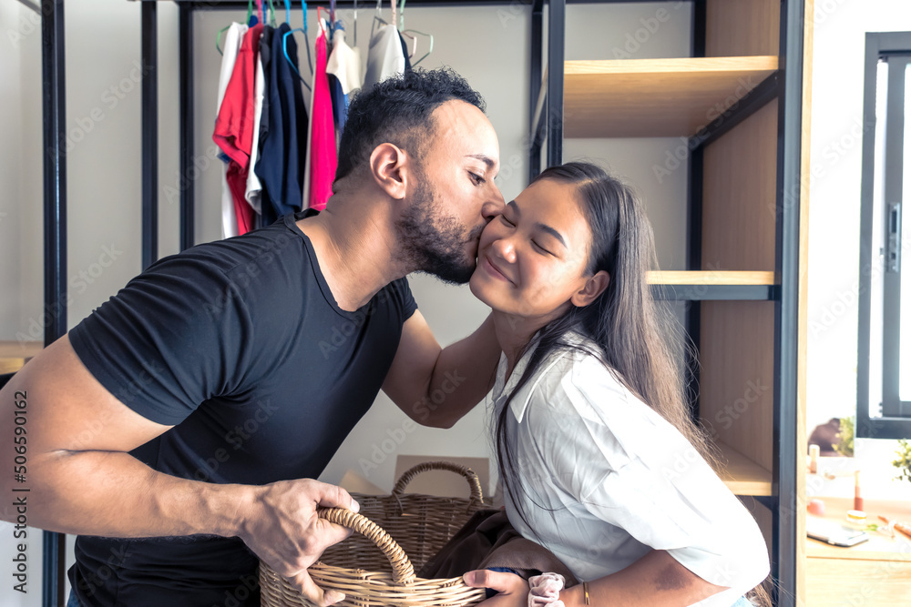 newlywed man kissing Asian wife in walkin closet newlywed man kissing Asian wife in walkin closet