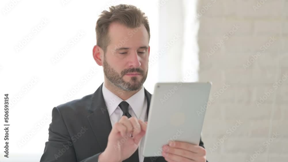 Attractive Young Businessman using Tablet in Office Attractive Young Businessman using Tablet in Office