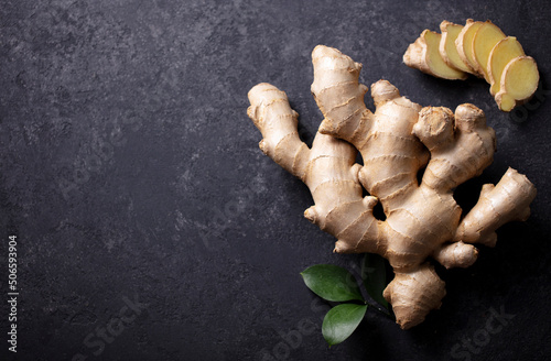 Fresh ginger root with slices. Dark background. Copy space. Top view.