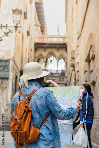 Latin tourist consulting the street map in the Gothic quarter of Barcelona (Spain), selective approach to the hat, travel concept.