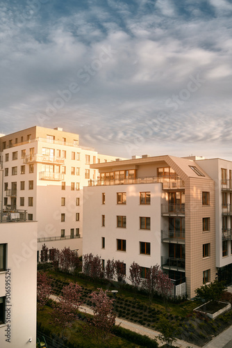 The apartment building at sunset. Condominium construction in the evening. Strong sunlight falls on the low-rise modern residential building © AlexGo