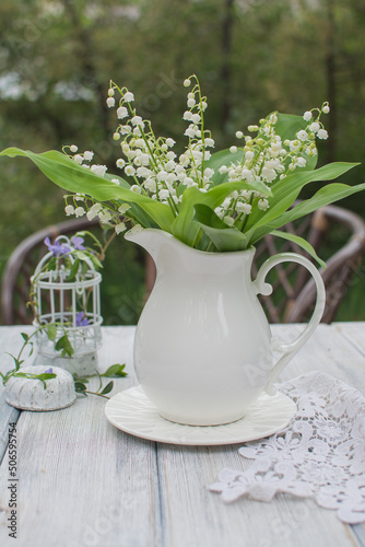 Bouquet of lilies of the valley in an antique white ceramic jug.
