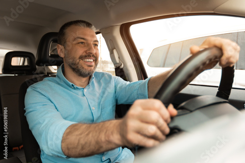 Smiling guy driving new car in city