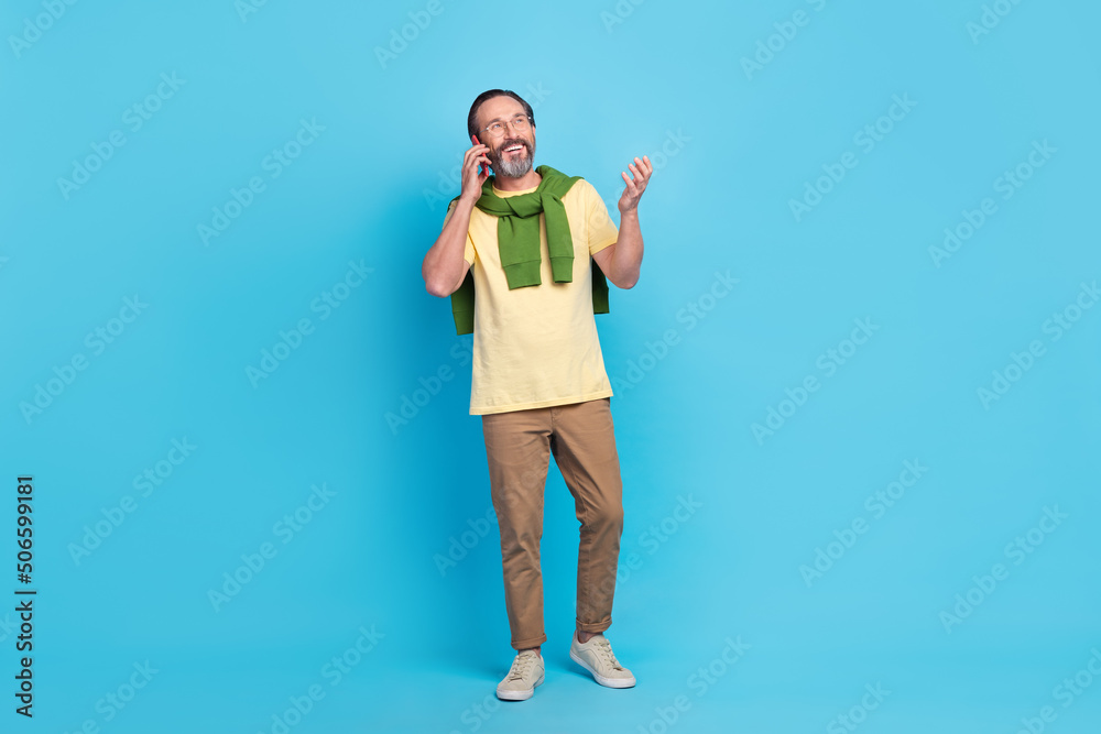 Full size photo of positive nice person walk speak telephone isolated on blue color background