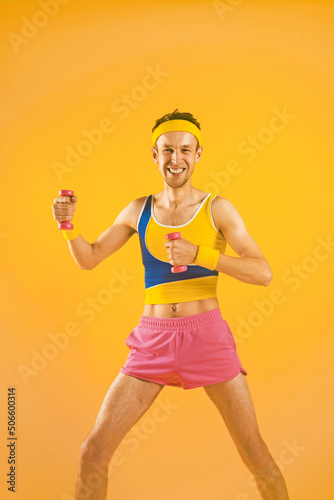 A thin funny guy in sports clothes with small dumbbells.