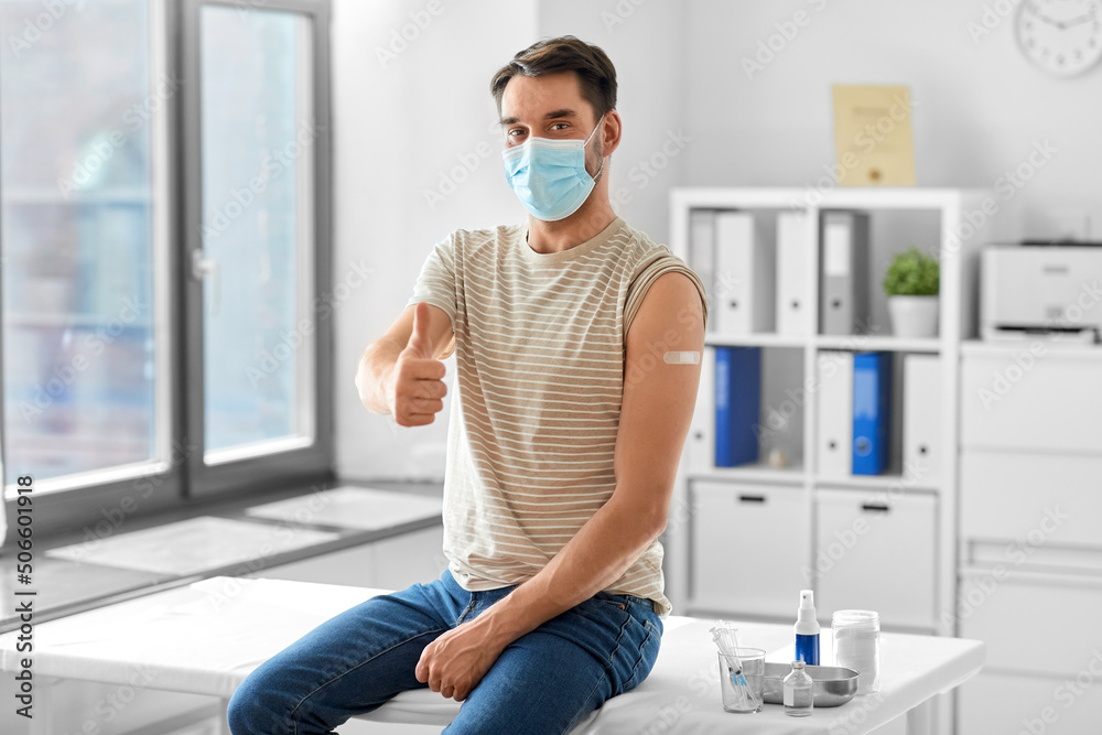 health, medicine and pandemic concept - happy male patient in mask with patch on his arm after vaccination showing thumbs up gesture at hospital health, medicine and pandemic concept - happy male patient in mask with patch on his arm after vaccination showing thumbs up gesture at hospital