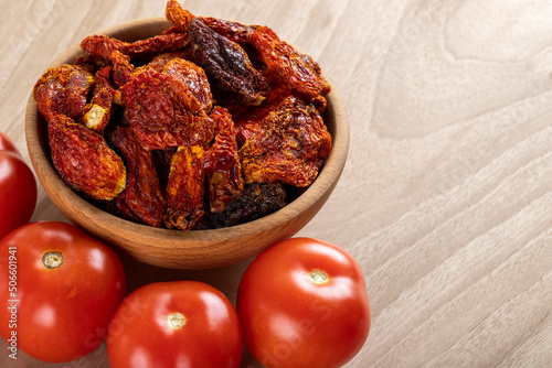 Fresh tomatoes and sun dried tomatoes together on wooden background