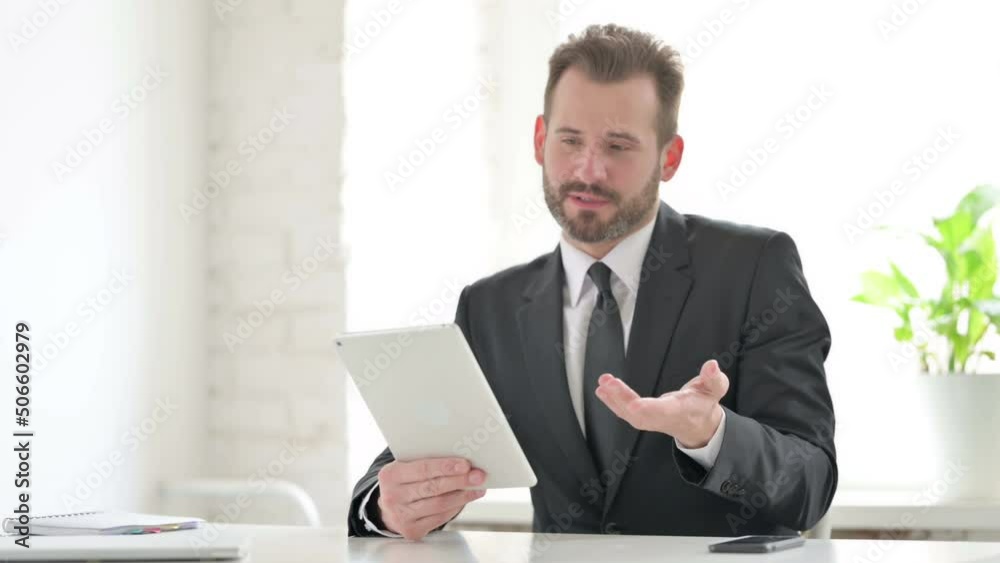 Young Businessman making Video Call on Tablet in Office Young Businessman making Video Call on Tablet in Office