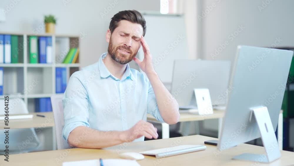 Exhausted, overworked office worker sitting in the workplace with a severe headache massaging his head. unhealthy Tired male employee in pain ache sick Stress at work sedentary working computer Exhausted, overworked office worker sitting in the workplace with a severe headache massaging his head. unhealthy Tired male employee in pain ache sick Stress at work sedentary working computer