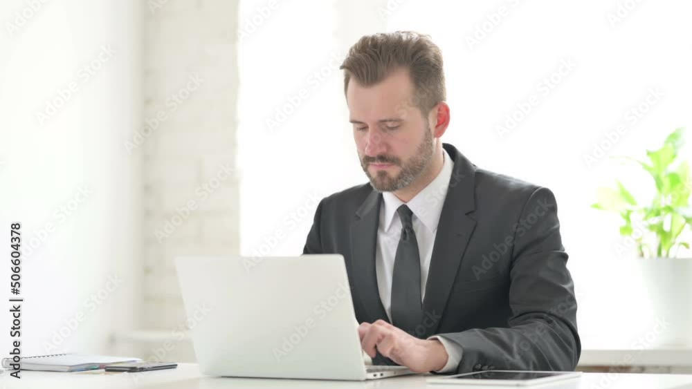 Young Businessman having Back Pain while using Laptop in Office Young Businessman having Back Pain while using Laptop in Office