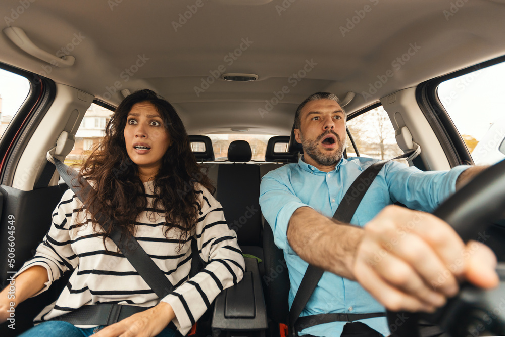 Scared couple driving car, front portrait, windshield view