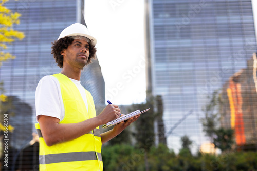 Young arhitect with helmet. Man using digital tablet. photo