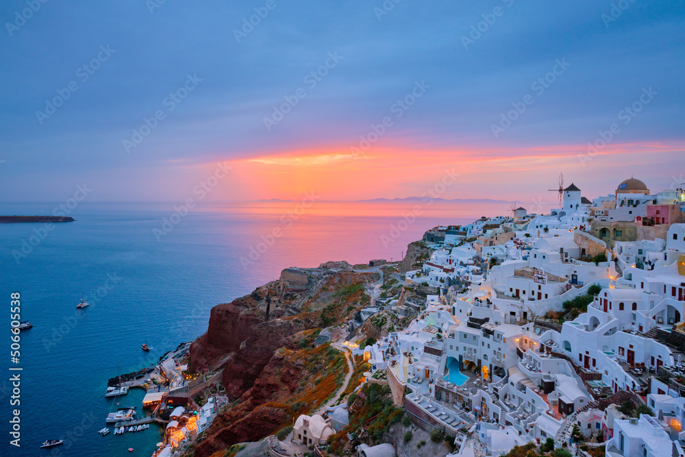Fototapeta premium Famous greek iconic selfie spot tourist destination Oia village with traditional white houses and windmills in Santorini island on sunset in twilight, Greece