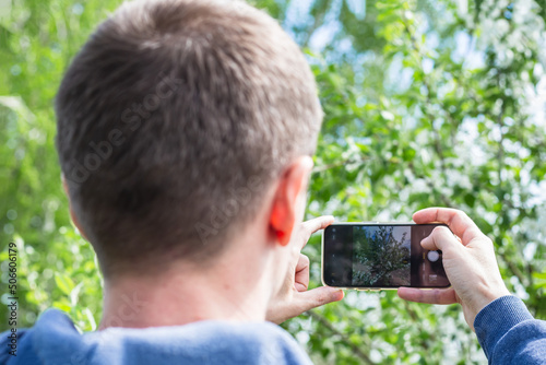 middle aged man taking photo of apple flowers or apple blossom with smart phone technology concept.