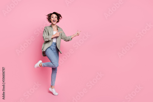 Full length photo of amazed excited person indicate finger empty space isolated on pink color background