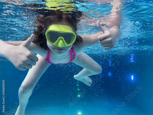Smiling child in goggles swim, dive in the pool with fun - jump deep down underwater. Healthy lifestyle, people water sport activity on summers. 