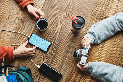 Family planning vacation trip. Woman searching travel destination and routes using navigation map on mobile phone. Charging smartphone with power bank. Using technology while travelling