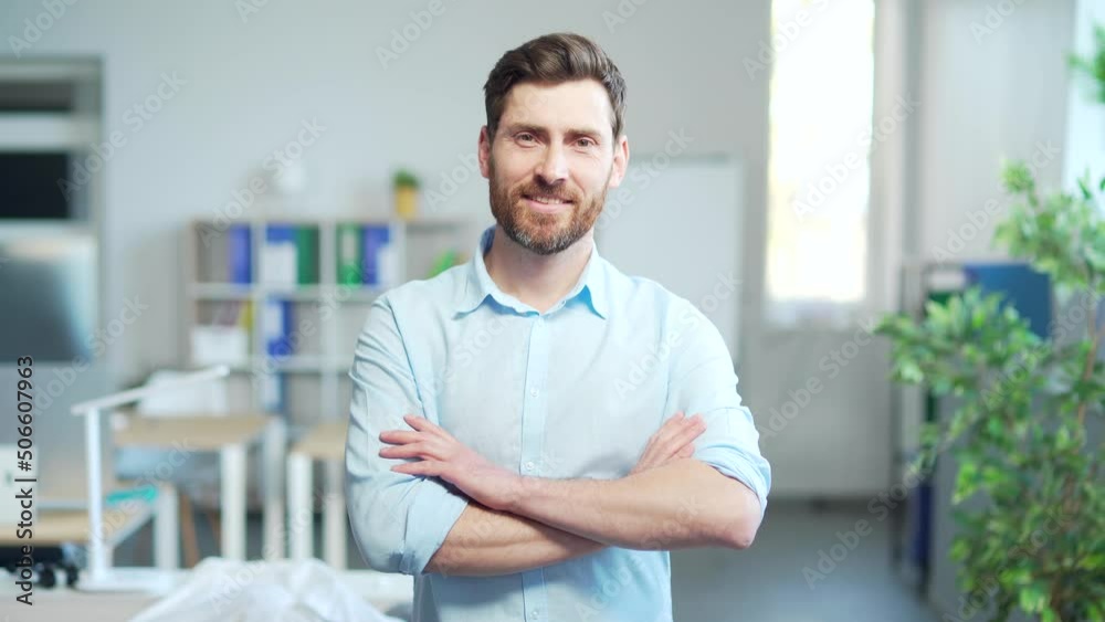 portrait of a handsome caucasian bearded office worker, employee of an entrepreneur who looks at the camera and smiles. Happy and cheerful male clerk at work. Businessman in a modern business office