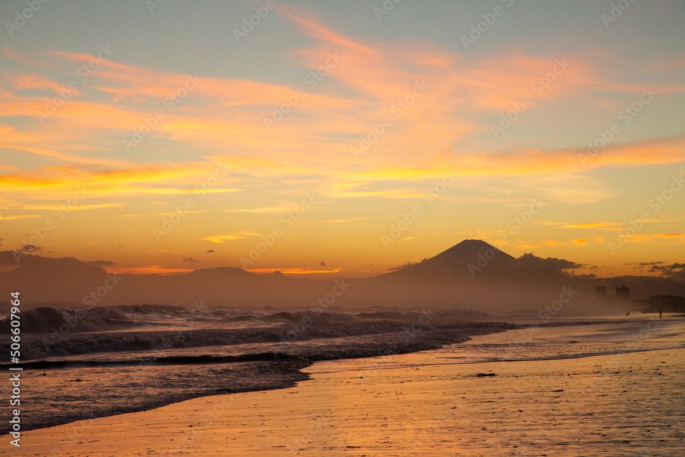 海岸から沈む夕焼けの富士山