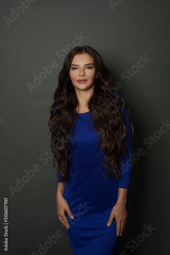 Beauty perfect woman model with long, healthy and shiny wavy hair wearing blue dress. Beautiful female with curly hairstyle .