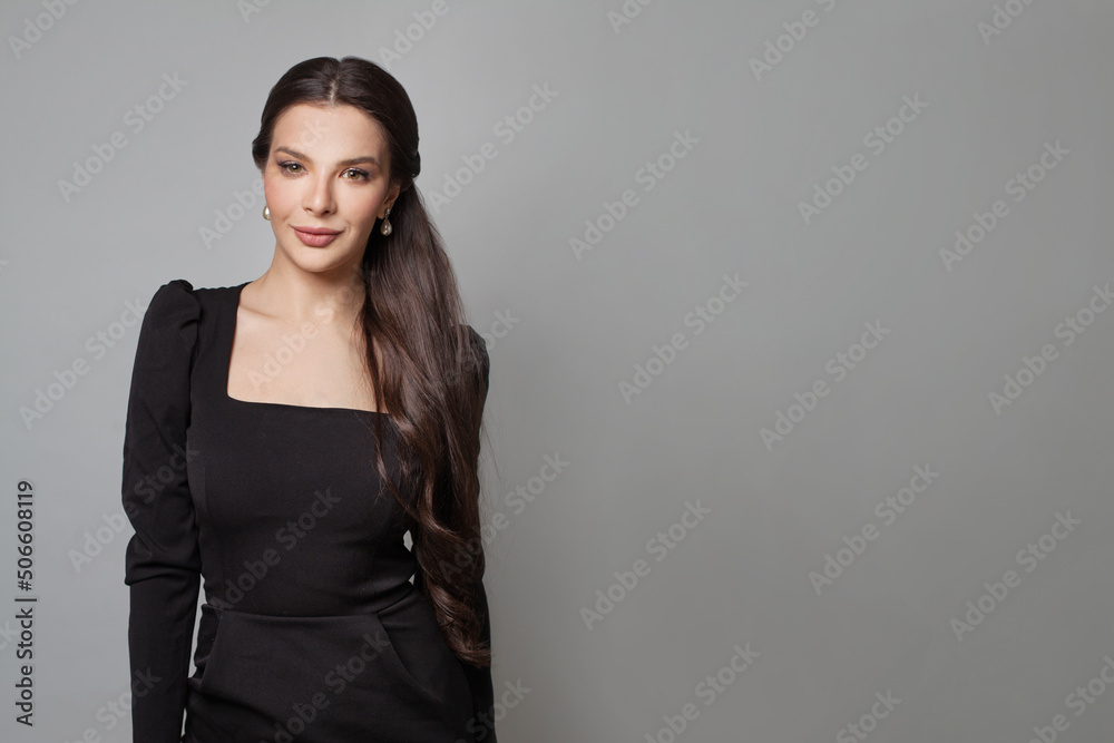 Brunette female model in black dress smiling on gray banner background Brunette female model in black dress smiling on gray banner background