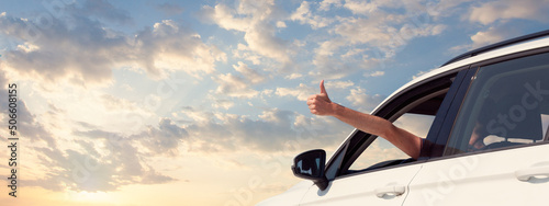 Happy man holding hand outside open window car with sky clouds background. People lifestyle relaxing as traveler on road trip in holiday vacation. Transportation and travel concept