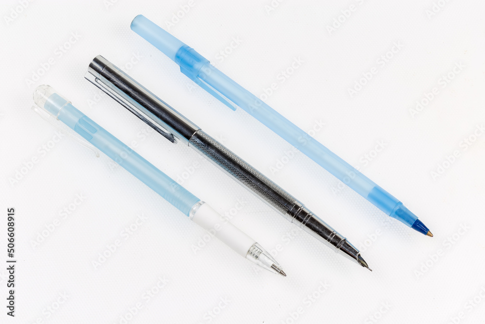 Modern ballpoint pens and fountain pen on a light surface